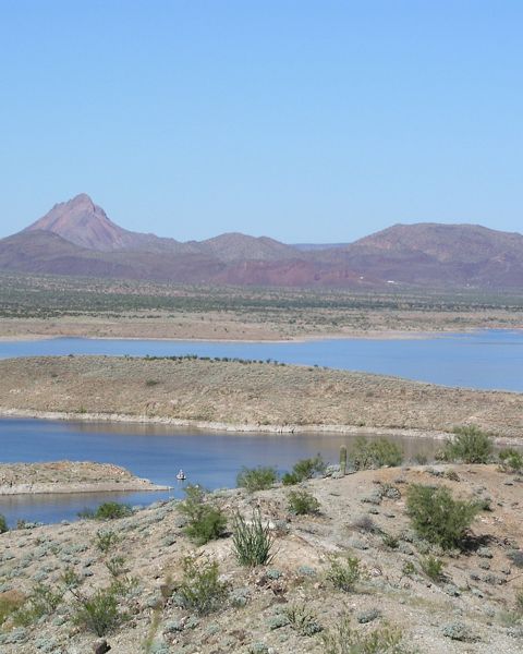 Expansive view of a river winding through an arid landscape with mountainous terrain in the background.