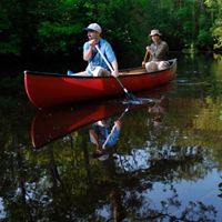 Two people paddle a canoe through still waters