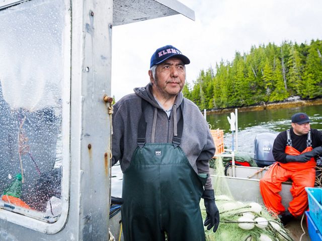 Ernest (Charlie) Mason with son, Ernie Mason (background) looks for jumping salmon in the Kitasoo Bay, a sign that there is a larger school to be caught under the surface. Cha