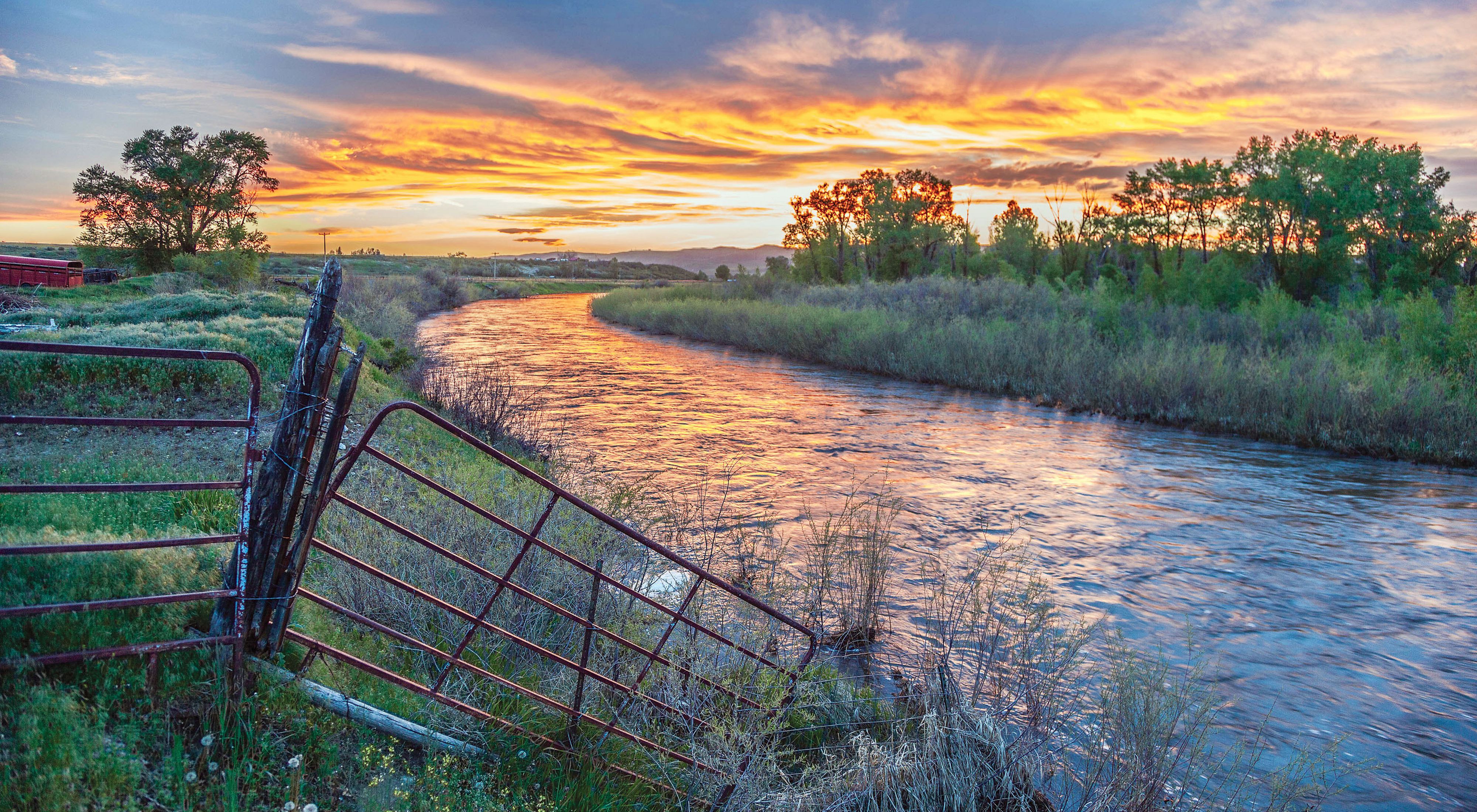 A river flowing through a ranch at sunset.