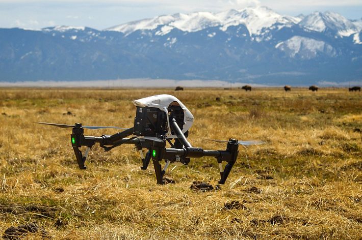 Closeup of a drone hovering over a grassy plain.