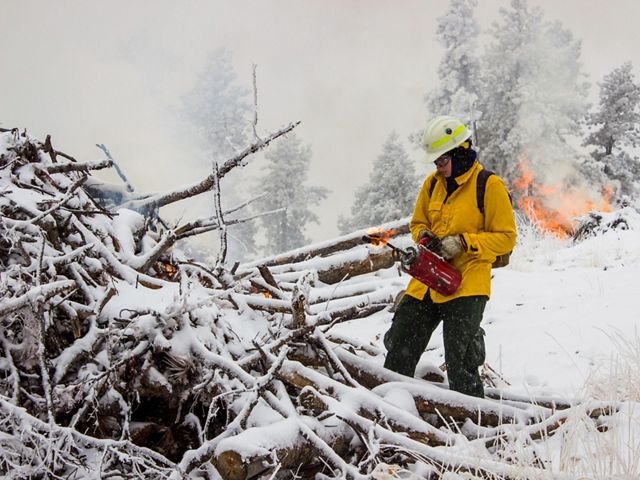A fireworker burns brush piles that have been cut to reduce wildfire risk and protect clean water in the Denver, Colorado, area.