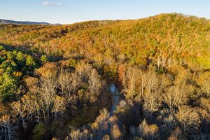 An aerial view of a river winding through an Appalachian forest in autumn.