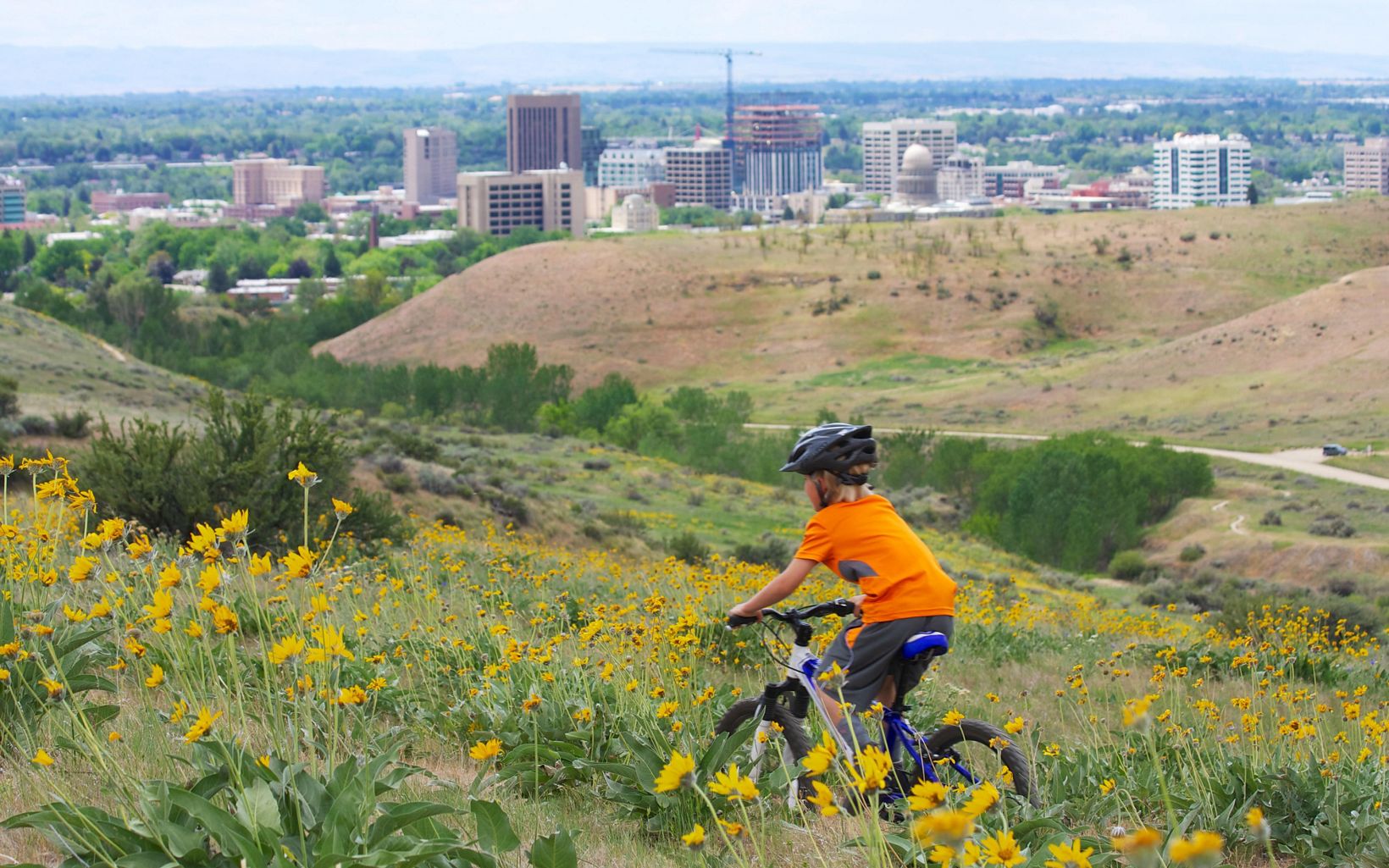 child on a bike rides through hills overlooking city of boise