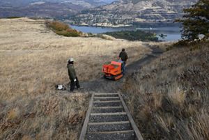 Two people on a trail with an orange shovel.