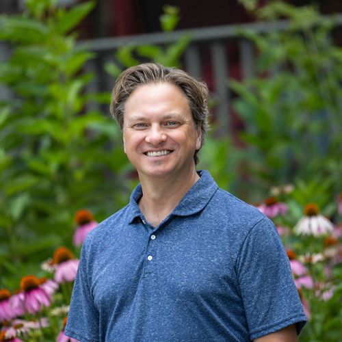 Person smiling in front of nature.