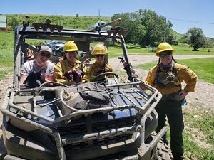 2024 Academy participants smile while sitting in a utility terrain vehicle. 