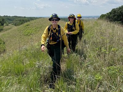 firefighters in line walking down a hill.