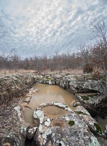 A rock formation containing pools of standing water from Turkey Creek, one of the many water features found on the Pearl Jackson Crosstimbers Preserve.