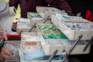 Two tackle boxes are set up on a table to create a mobile lab. The boxes expandable compartments hold a variety of supplies, including items for collecting blood samples.