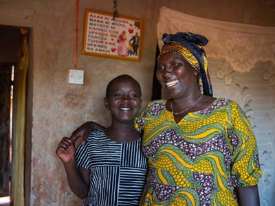 A woman and her daughter standing in their house.