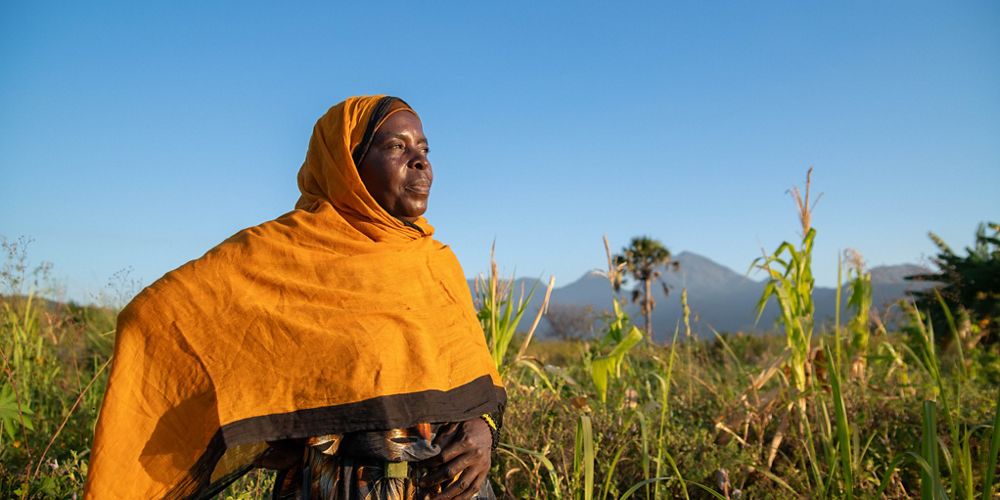 A woman in an orange headscarf standing in a field.