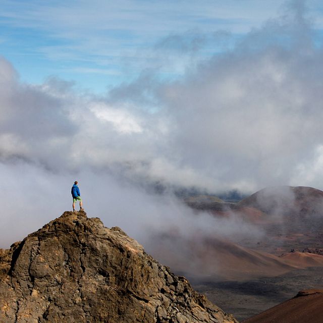 person standing on a mountain looking at a foggy landscape