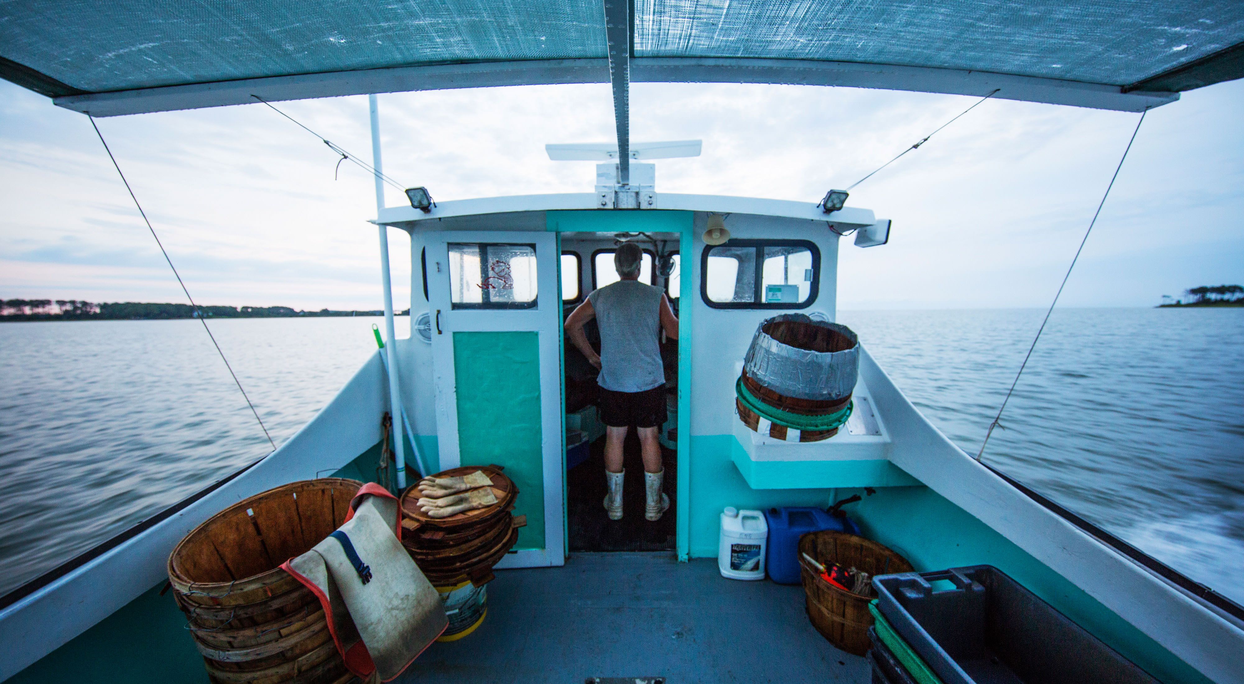 A man stands in the wheel house of a crab boat.