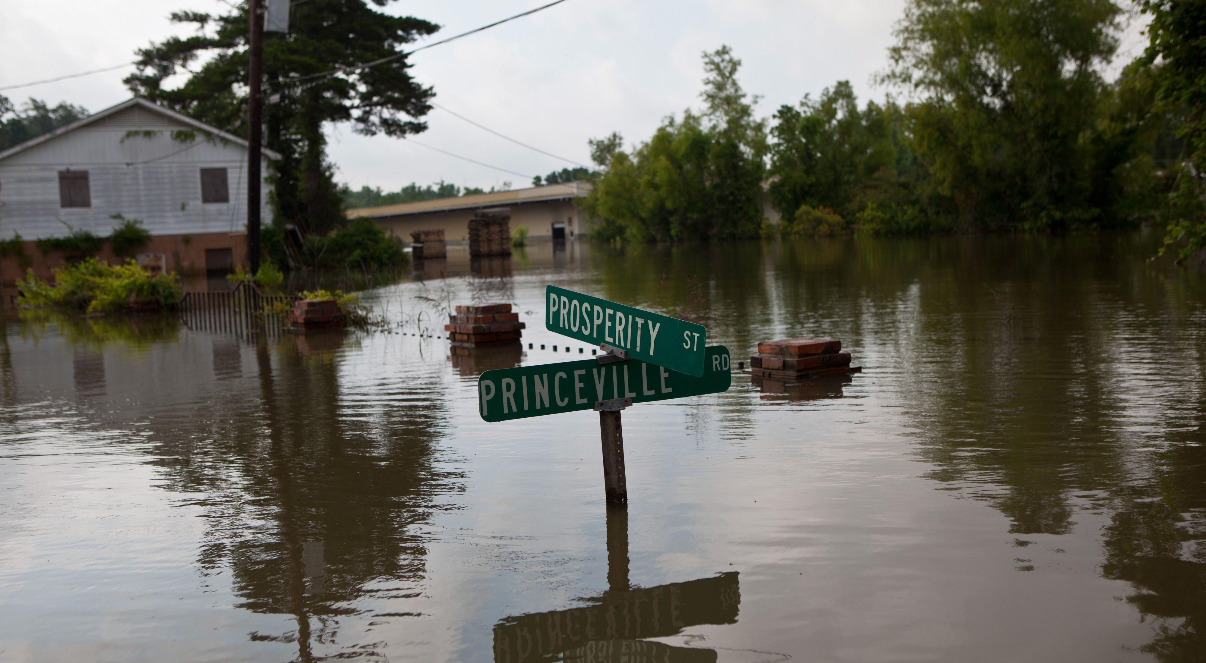 A street sign emerges from water in a flooded community.