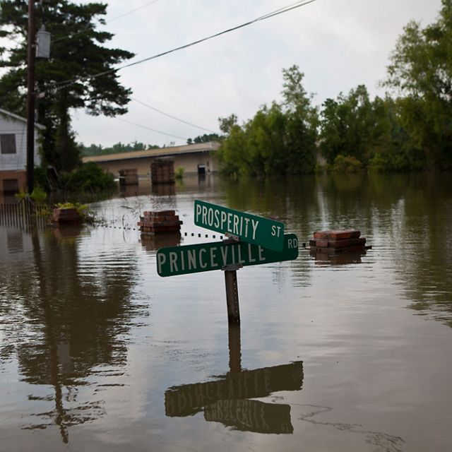 A street sign emerges from floodwaters in a neighborhood.