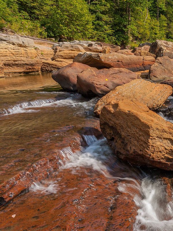 Water tumbling over large rust-colored boulders.