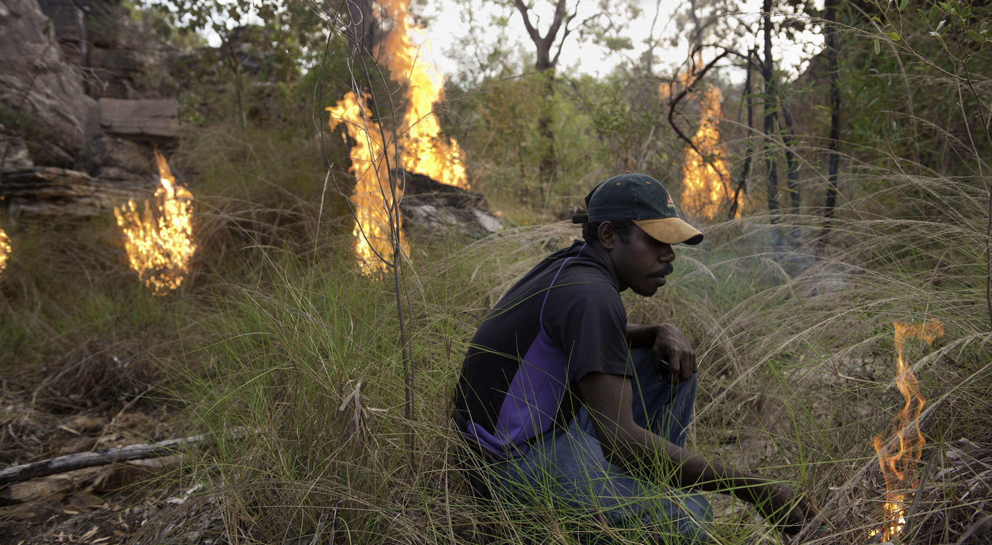 a man tending a controlled burn on a grassland