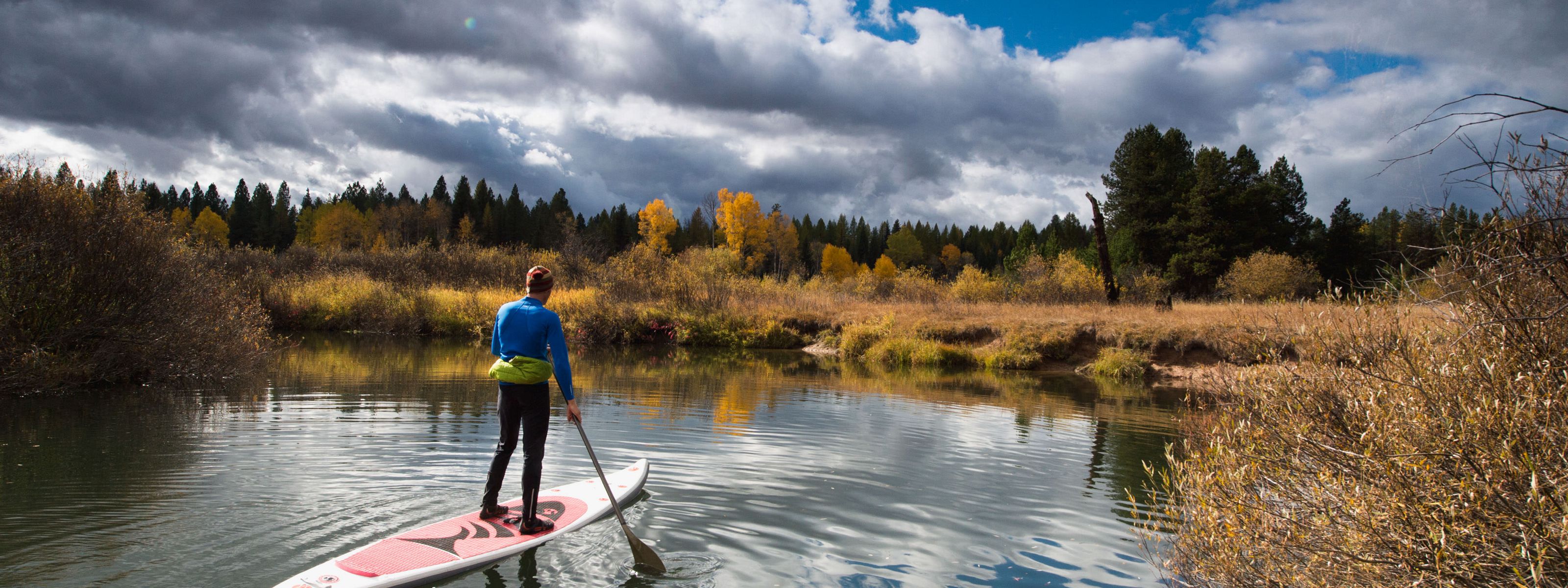 Person paddling on a standup paddleboard along the Clearwater River Canoe Trail in Montana.