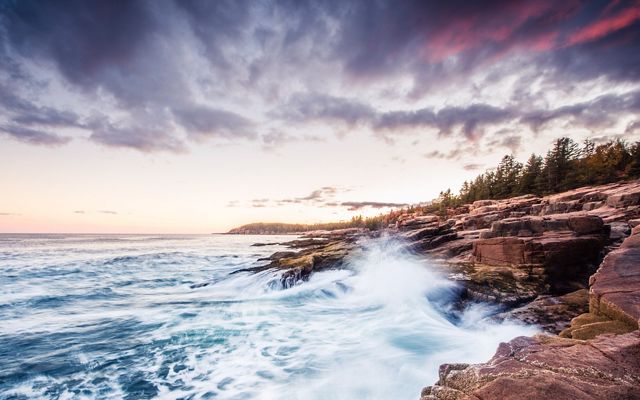 Blue waves crash against a rocky shore at Acadia National Park