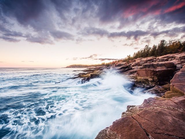 Blue waves crash against a rocky shore at Acadia National Park