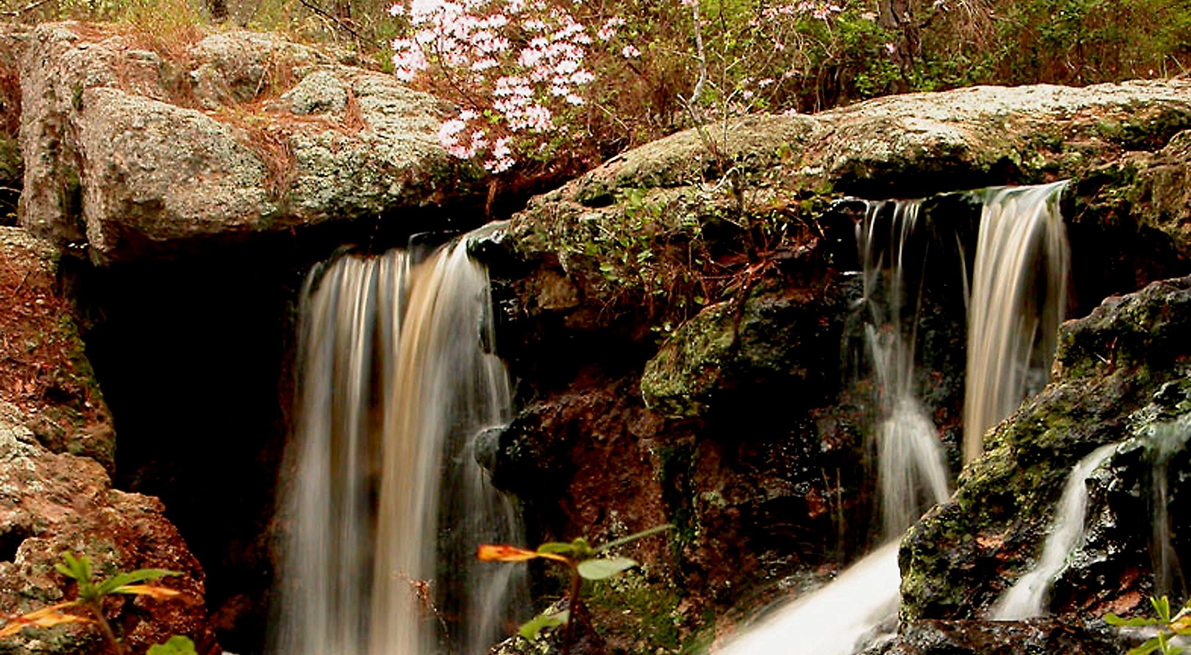 Waterfalls cascade down moss covered rocks.
