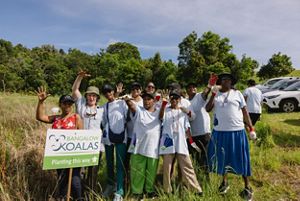 A group of people gather outdoors around a sign.