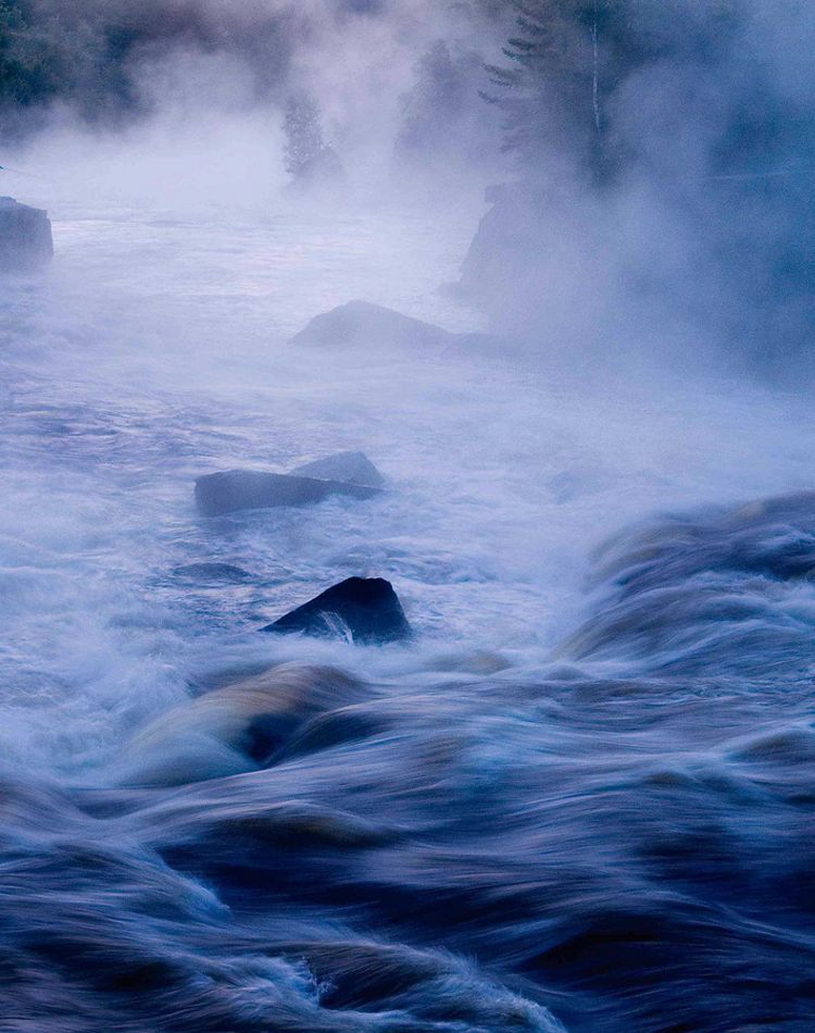 Fly fisher on rock on misty penobscot river in maine