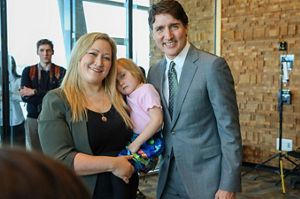 Dani Shaw holds her daughter in her arms and smiles while standing next to justin trudeau