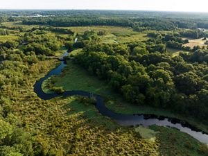 Aerial photo of the Nemasket River winding from the bottom right to top left of the image, surrounded by greenery dotted with a few structures.