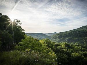 Green forested hills under a partly cloudy sky.