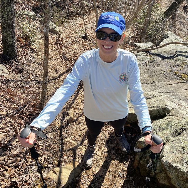 Candid photo of a smiling woman hiking on a trail.