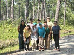 Group of interns smiling with a longleaf pine forest in the background.