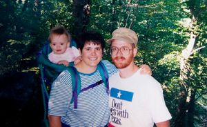 An old photo of a family with a baby on a backpack carrier.