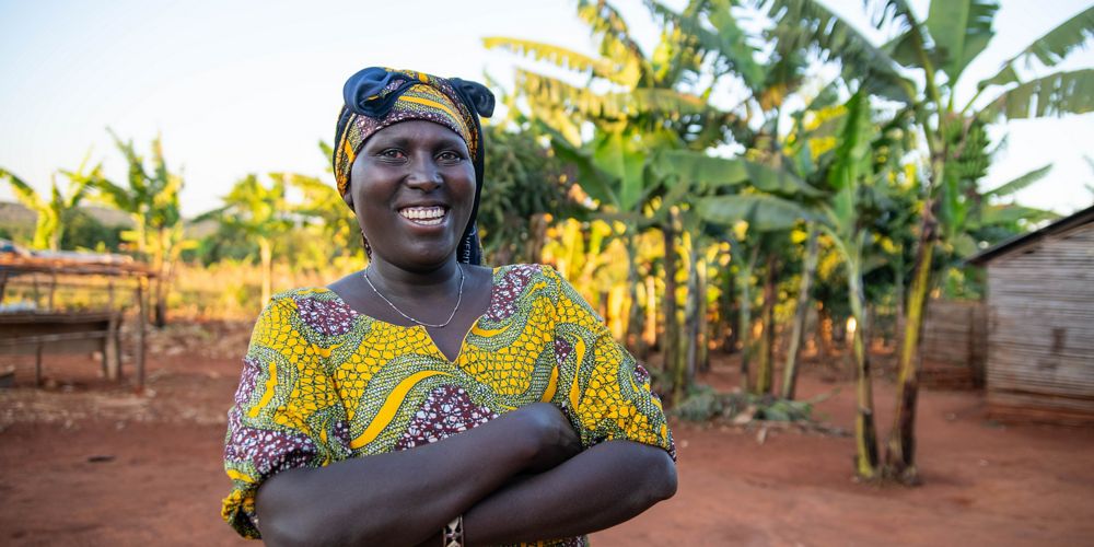 A smiling woman standing near trees.