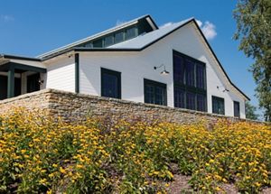 An image of a grand farmhouse with flowers blooming in front of it. 