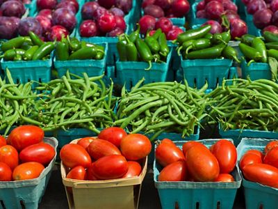 Fresh tomatoes, green beans, and plums at a farmers market.