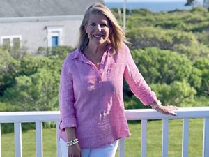 A woman in a pink top with the ocean in the background.