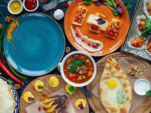 a spread of brightly colored food and dinner plates on a table