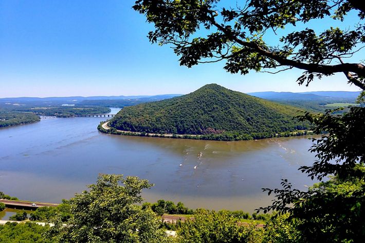 A vista view overlooking a body of water with a small mountain in the center.