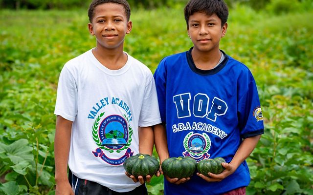 Two students hold freshly picked squash from their fields in Belize.