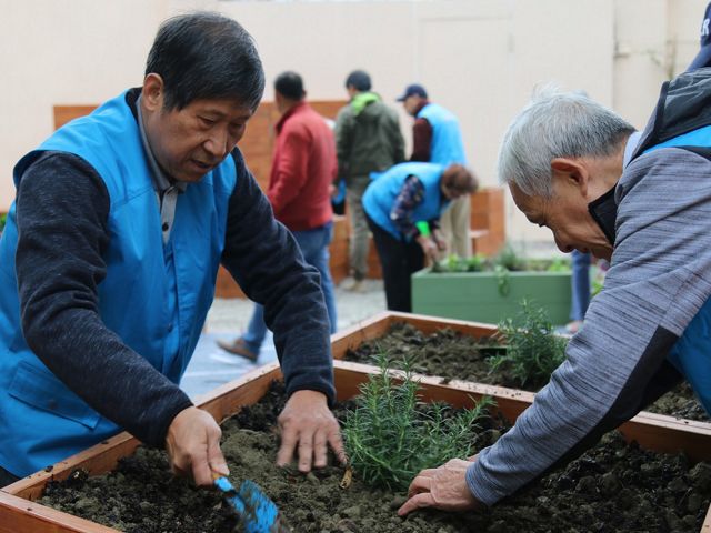 Two volunteers maintaining a raised bed in a habitat garden.