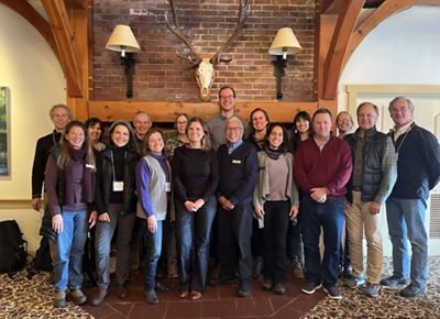 The members of the TNC Vermont Board of Trustees stand together in front of a fireplace and smile for a group photo.