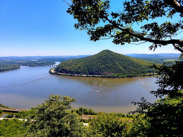 A vista view overlooking a body of water with a small mountain in the center.