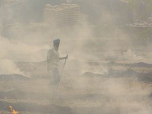A farmer is obscured by smoke as his field burns.