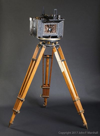 An old camera on wooden legs.