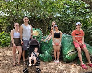 A family stands in front of a dinosaur statue.