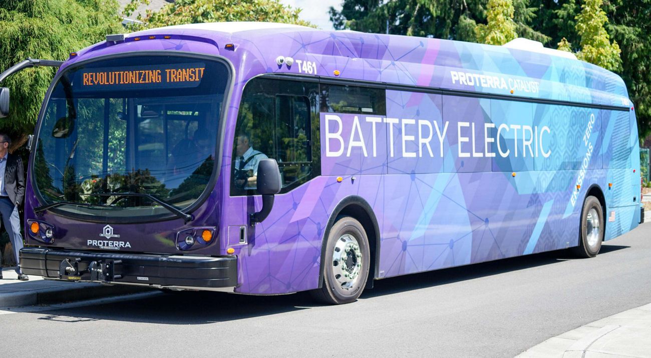 a purple and blue bus with "battery electric" on the side.