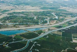 An aerial photograph features a river flowing through a mixed use landscape. 