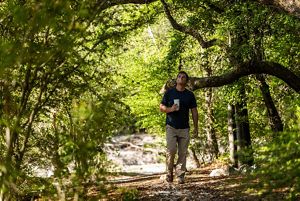A man walks along a forested trail.